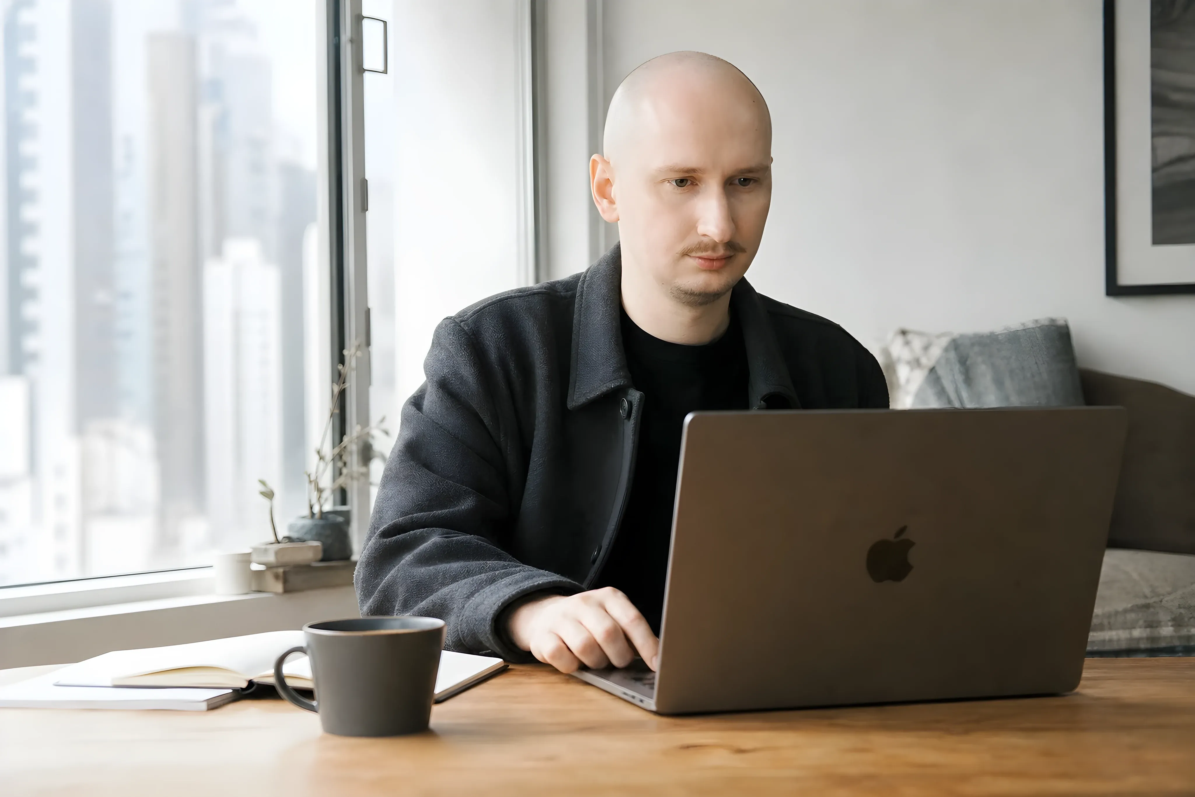 Simon Halimonov working on a MacBook by the window of his studio